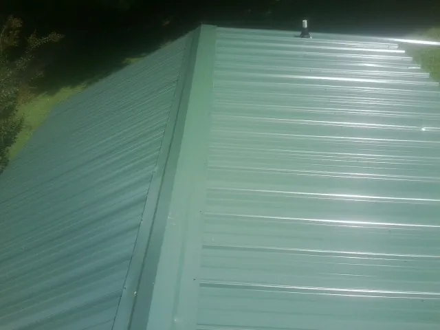 New green metal panels meeting at the ridge of a roof — Flat Roof Repair work by our crew in Tustin