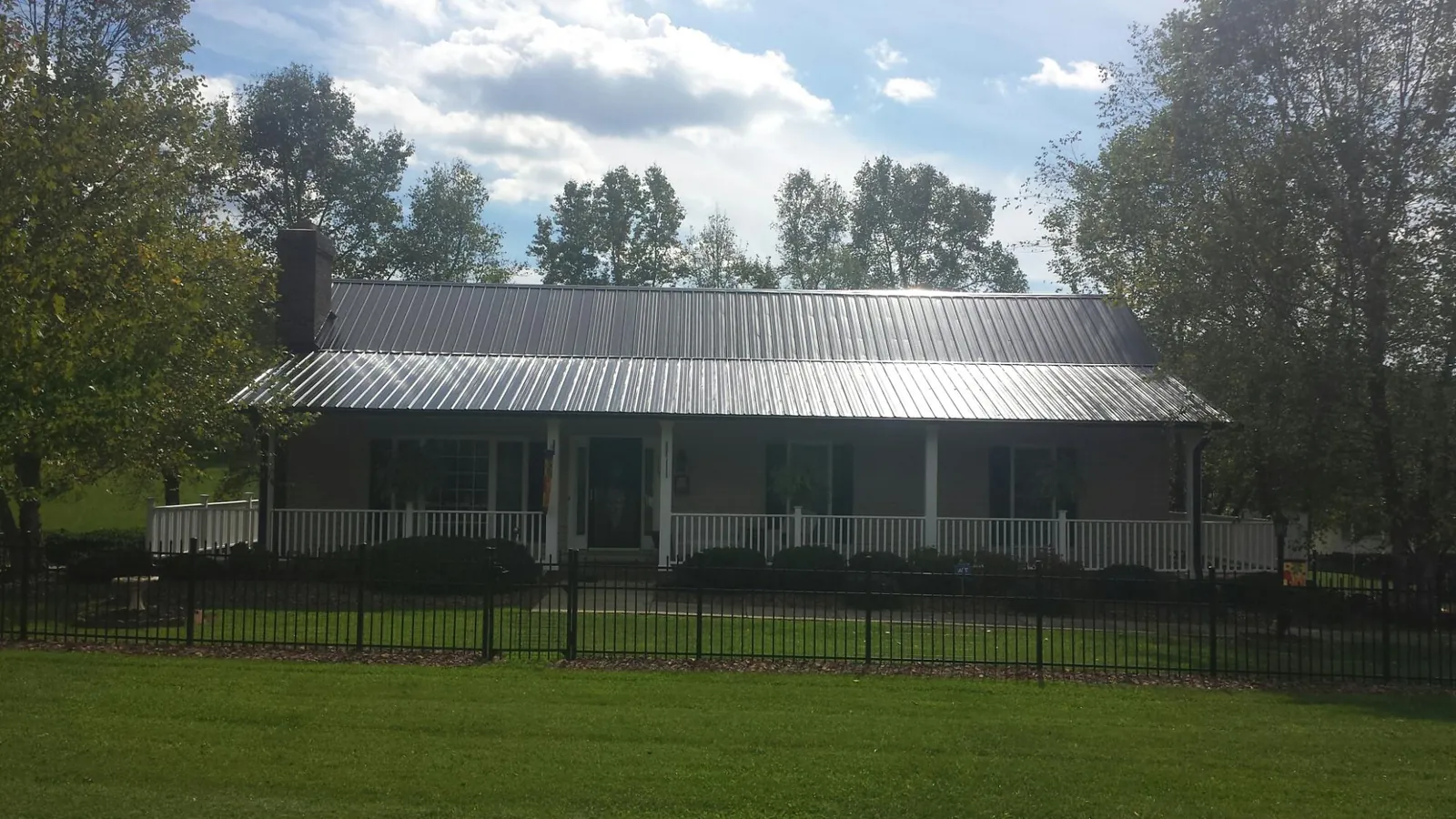 Gray metal roof on a brick ranch with a full width front porch — Gutter Guard Installation work by our crew in Tustin