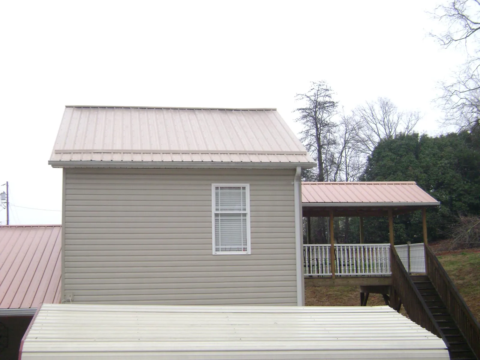 Tan metal roofs on a two story addition and attached porch, from a Roof Replacement job in Tustin